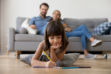 Cute kid girl playing on warm floor at home, preschool little girl drawing with colored pencils on paper spending time with family in living room, creative child activity, underfloor heating concept