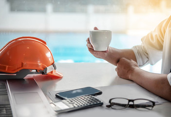 Young Architect man doing hand holding coffee mug while taking relax  a break from work. Project...