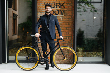 Lifestyle, transport and people concept.Bearded young man standing with bicycle on city street over brickwall