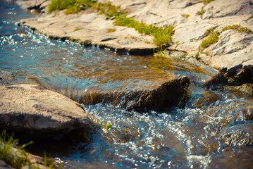 Stream with rocks in the sunshine at mountain