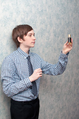 The young Russian guy holds a bottle of men's perfumery water in hand.
