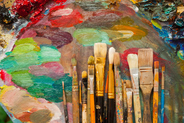 Obraz premium Paints, brushes and palette on the wood background. The workplace of the artist. Banner for school