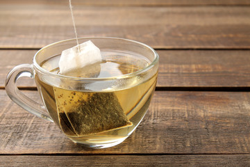 Tea bag in a glass cup on a brown wooden background. to make tea