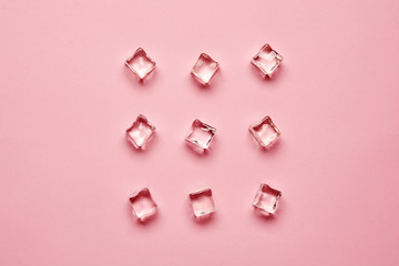 Set pieces of pure ice cubes on pink background with copy space. Top view or flat lay.