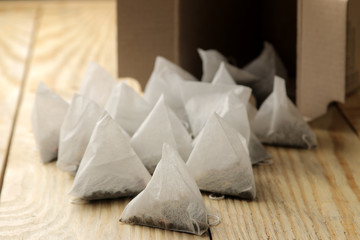 tea bags pyramid fall out of the box close-up on a natural wooden table