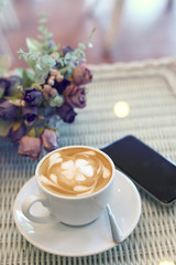 beautiful frangipani plumeria flower art latte of hot coffee drink tasty in cafe restaurant with mobile phone on table
