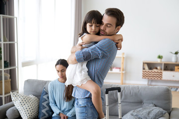 Sad little girl upset by father leaving embracing dad, depressed child saying goodbye hugging daddy going away, kid and parents divorcing breaking up, family separation, shared custody concept - obrazy, fototapety, plakaty