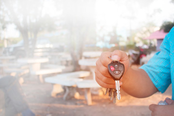 Men's hands are showing car keys with unlocking symbols and alarms.