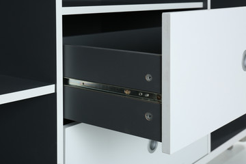 Stylish shelving unit with open drawer, closeup. Furniture for wardrobe room