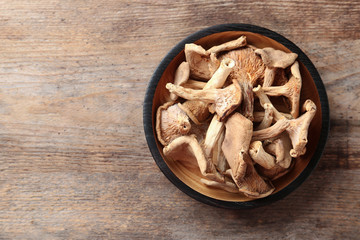 Plate of dried mushrooms on wooden background, top view. Space for text