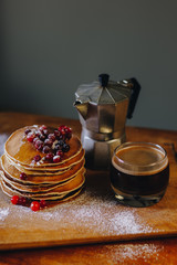 Stack of pancakes with maple syrup and cranberries and coffee
