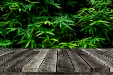 empty wooden board, table or modern wooden terrace with image of dark green plant tropical bamboo leaf texture background, copy space for display of product, object presentation, advertisement concept
