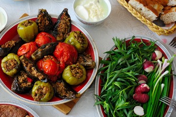 Azerbaijani dolma with eggplant, tomato and pepper, yogurt, greenery and bread on the table