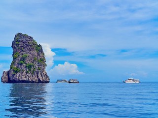 Pleasure boats with tourists are located near one of the stone islands of the archipelago of Koh Ha (Thailand)