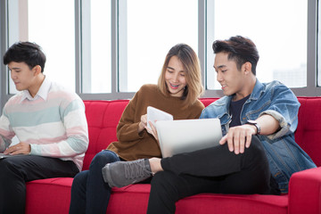 Group of happy university students sitting on sofa during break together  with smartphones , laptop and tablet pc computers . Startup Teamwork . entrepreneur meeting .friendship .fun