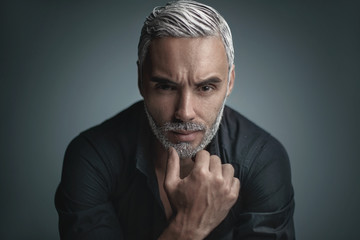 Fototapeta premium A man with blond hair and a beard looks into the camera.