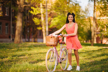 Latin woman in pink dress with flowers and pink bicycle.