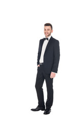 handsome smiling man posing in black tuxedo and tie bow isolated on white