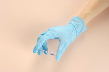 Ampoule for injection in hand. Latex gloved hand. Close-up. Light background.