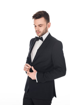 handsome man posing in elegant black tuxedo and tie bow isolated on white