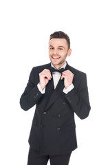 cheerful elegant man posing in black tuxedo and tie bow isolated on white