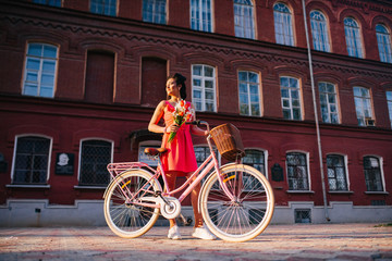 Obraz premium Latin woman in pink dress with flowers and pink bicycle.