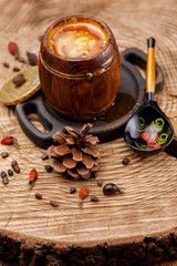 Barrel with honey and painted wooden Russian spoon on a wooden saw with cedar cones.