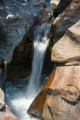 Fototapeta na wymiar Water cascade of the river Toce among the rocks smoothed in the gorges of the ravines of Uriezzo in val Antigorio, in Piedmont, Italy.