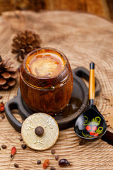 A barrel with fresh honey and a painted wooden Russian spoon on a wooden sawn with pine cones.