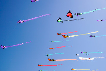 angle view of a colorful kite flying with waving red bow in a deep blue sky with the light of the...