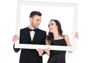 cheerful couple in black clothes posing with frame, isolated on white