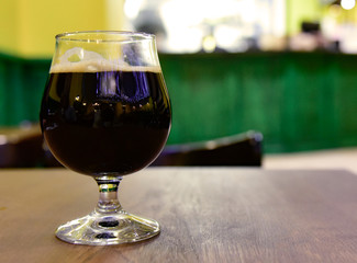 A glass of dark beer on the bar table