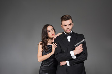 beautiful couple of secret agents with handgun, isolated on grey