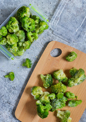 Frozen broccoli in lunch box on a concrete background with space for text.