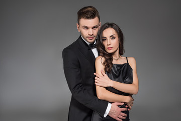 handsome boyfriend hugging beautiful elegant girl isolated on grey