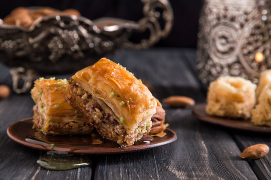 Close up, macro. Traditional honey baklava, nuts. Pottery and silverware. Dark wooden background.