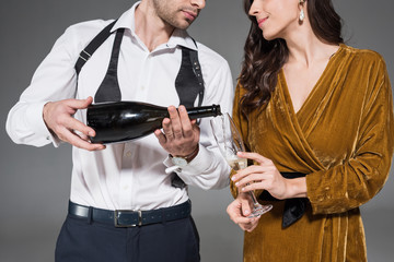 cropped view of boyfriend pouring champagne for girlfriend isolated on grey