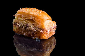 Close up. Turkish traditional baklava from dough, pistachios and honey. Isolated on black background.