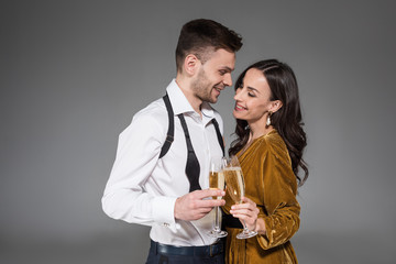 beautiful happy couple holding champagne glasses isolated on grey