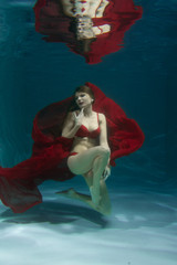 pretty caucasian long hair woman swimming underwater in red sexy lingerie alone in the deep