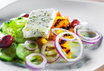 greek salad with cheese, tomato, olive, pepper, onion in white plate