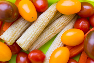 School lunch box. Candies, baby corns, carrot and tomatoes in green plastic container