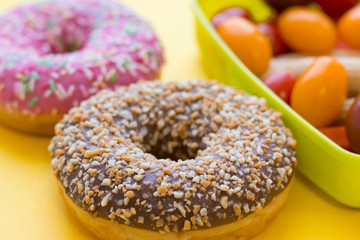 School lunch box. Donats, candies, baby corns, carrot and tomatoes in green plastic container