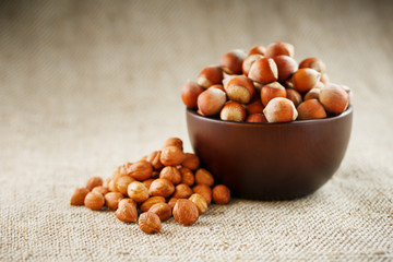 Peeled hazelnuts in a wooden, dark brown cup on a burlap cloth. Super Food, Raw.