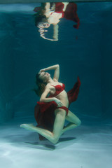 pretty caucasian long hair woman swimming underwater in red sexy lingerie alone in the deep