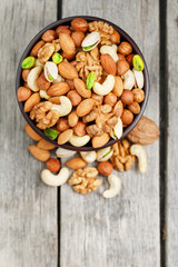 Wooden bowl with mixed nuts on a wooden gray background. Walnut, pistachios, almonds, hazelnuts and cashews, walnut.
