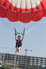 Young happy girl with short hair cut on water red parachute