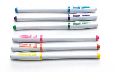 Six multi-colored ball point pens on a white background