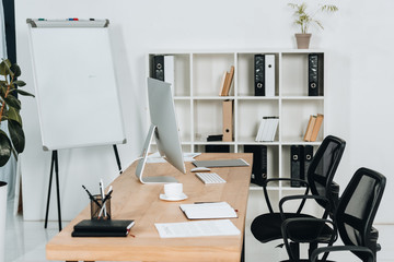 modern office interior with desktop computer and office supplies, chairs and whiteboard
