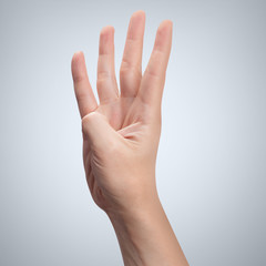 Hand with four fingers up on gray background